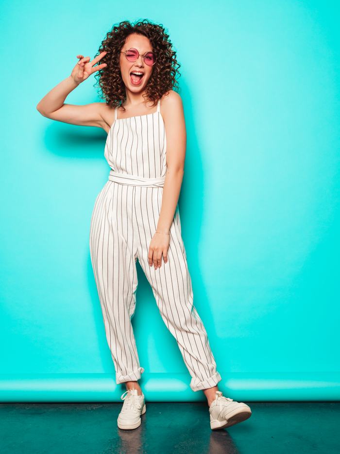 Smiling model with afro curls against a blue wall