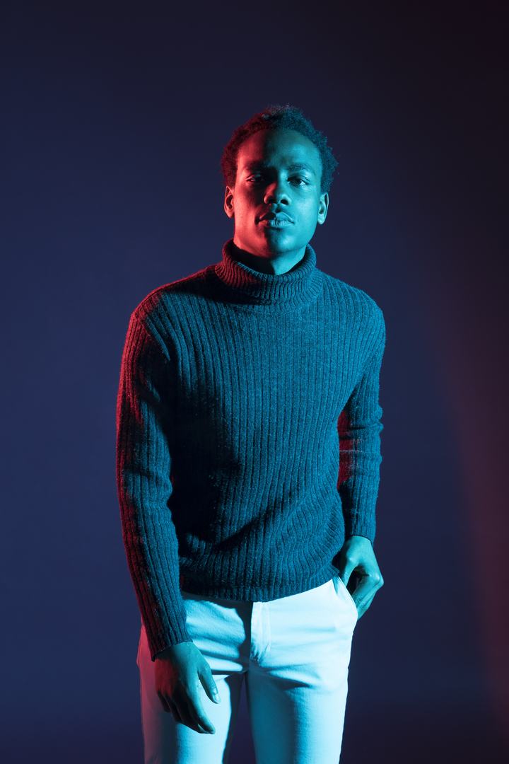 Male model in a turtleneck under blue and red studio lighting
